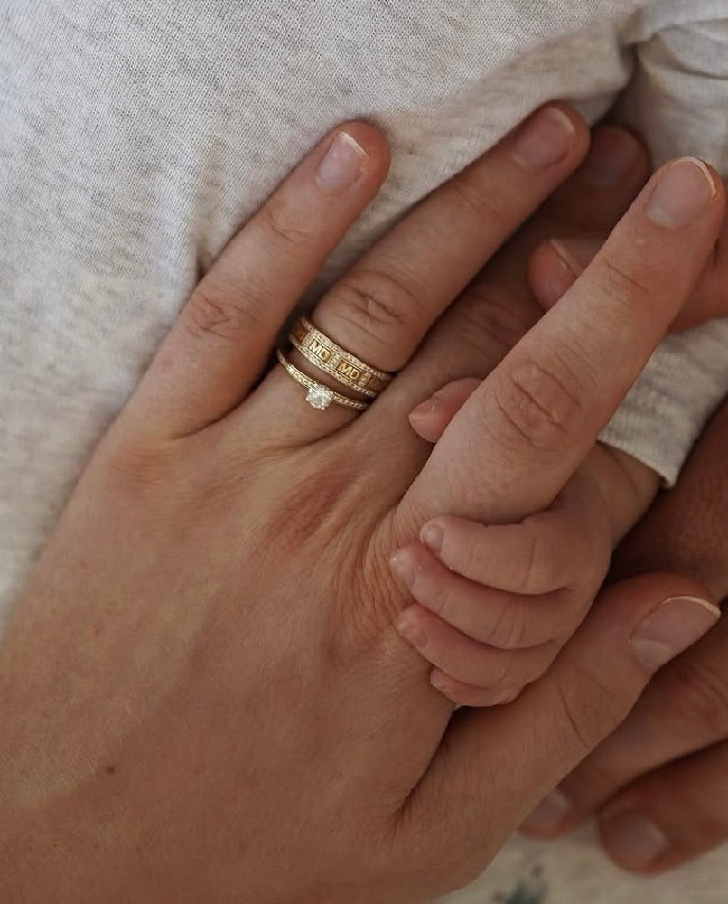 Hand mit AIMÉ Initialenring und Babyhand